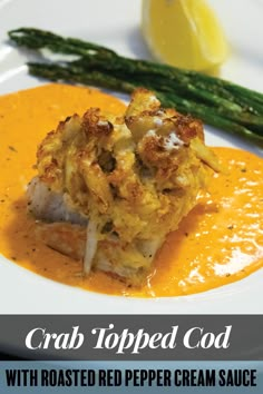 crab topped with roasted red pepper cream sauce and asparagus on a white plate