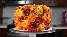 a cake with orange and yellow frosting flowers on a silver platter in a kitchen