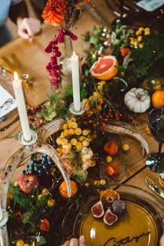 the table is set with candles, fruit and other decorations for an autumn dinner party