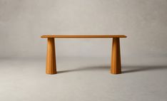 a wooden table sitting on top of a white floor next to a gray wall in an empty room