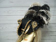 "Ladies Black woolen pirate hat/tricorn with black and beige ostrich feathers, light golden pleated trim with black braid, black satin cocarde with a golden sparkly jewel center. Sooo pretty! PLEASE MEASURE YOUR HEAD! This hat is 22.5\" for the inside circumference with a built-in hat sizer. Just cinch and tie. I cannot make the circumference bigger so please keep that in mind. This is not an oversized brim pirate hat. The upturn brim is about 4\". Check out my other pirate hats and other goodies in my etsy shop. Thank you for stopping by. Have a great day. I ship Priority mail. I ship many times a week. If you need your item quicker let me know your zip code and I can figure shipping rates for you. Please let me know if you have any questions I accept Paypal, credit cards and etsy gift ca Black Pirate Hat, Pirate Hat Aesthetic, Extra Fits, Wax Artist, Masquerade Prom, Tricorn Hat, Black Pirate, Hat Aesthetic, Pirate Halloween