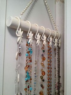 a bunch of necklaces hanging from a hook on a door handle with beads and chains attached to it