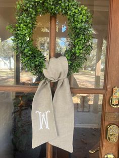 the front door is decorated with a wreath and monogrammed ribbon