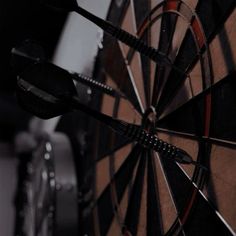 a dart hitting in the center of a bulls eye wall mounted darts target with black and red accents