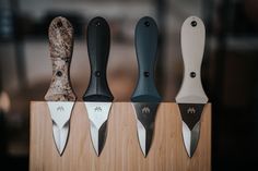 four knives are lined up in a row on top of a wooden block with black and white handles