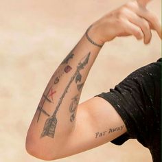 a man with tattoos on his arm pointing at something