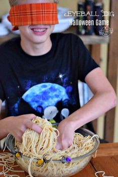 a young boy wearing a paper headband and making noodles with spaghetti in a bowl