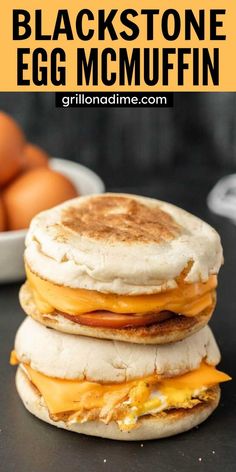 an egg and cheese breakfast sandwich on a black surface with eggs in the back ground