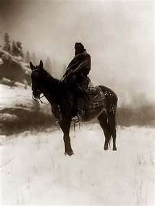 an old photo of a man on a horse in the snow