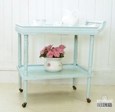 a small blue shelf with pink roses on it and a white teapot sitting on top