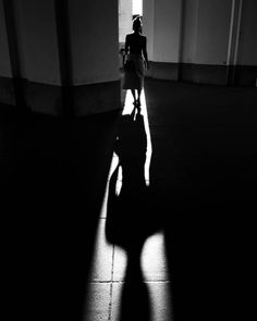 the shadow of a woman walking down a hallway