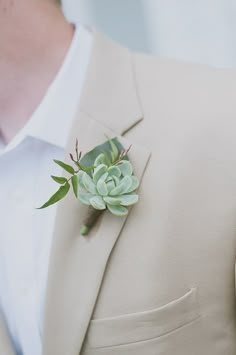 a man in a suit with a boutonniere and succulents on his lapel