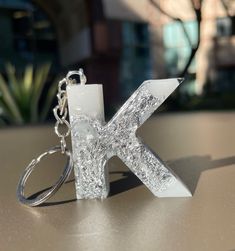 the letter k is made out of glass and has silver glitter on it's surface