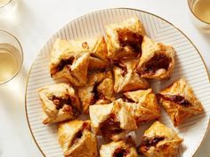 a white plate topped with pastries next to wine glasses