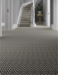 a carpeted hallway with stairs leading up to the second floor