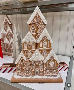 gingerbread houses are on display for sale in a store window, decorated with white and brown icing