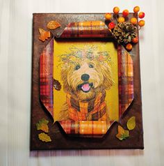 a wooden frame with a painting of a dog on it and autumn decorations around it