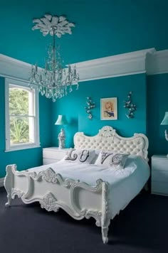 a bedroom with blue walls, white furniture and chandelier hanging from the ceiling