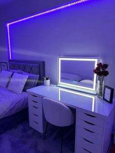 a white desk with a mirror on top of it next to a bed and flowers