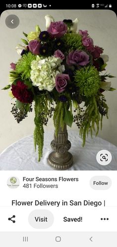 a vase filled with lots of flowers on top of a white tablecloth covered table