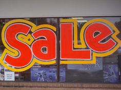 a store window with the word sale written in large red and yellow letters on it