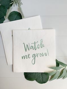 two cards with the words watch me grow written on them next to some green leaves