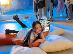 a woman laying on top of a pillow while using a laptop computer