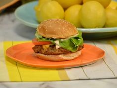 a chicken burger on an orange plate with lemons in the background