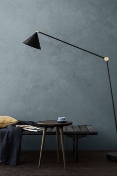 a table with a lamp on it next to a blue wall and a black couch