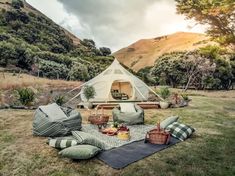 a tent set up in the middle of a field with pillows and blankets on it