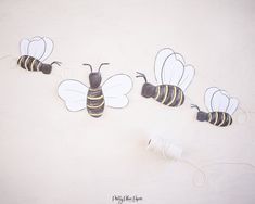 three paper cut out of bees sitting on top of a white surface with twine spools