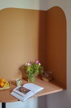 an open book sitting on top of a wooden table next to a vase filled with flowers