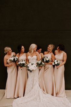 a group of women standing next to each other wearing dresses and holding bouquets in their hands