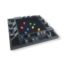 a black tray with dices and numbers on the inside, in front of a white background