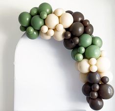 an arch made out of balloons in the shape of a wreath on a white wall