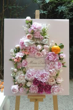 a card with flowers on it sitting on top of a easel in front of a tree