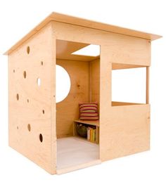 a small wooden house with holes in the roof and windows on each side, as well as a shelf for books