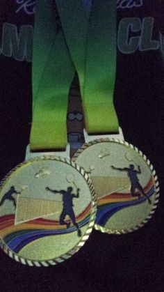 two medals with green ribbons around them