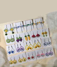 several pairs of earrings are displayed on a white sheet with flowers and butterflies in them