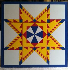 a yellow and blue quilt with an abstract design on the front, sitting on top of a table