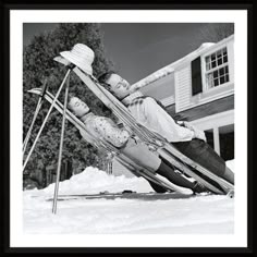 a man and woman sitting on skis in the snow with their heads turned to look like they're having fun