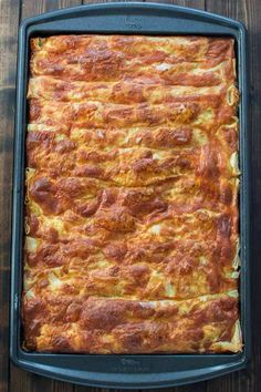 a casserole dish with cheese and meat in it on a wooden table top