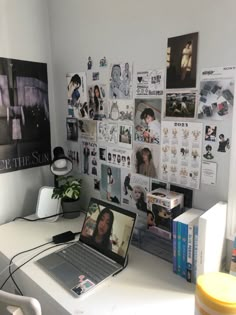 a laptop computer sitting on top of a white desk next to a pile of books