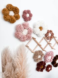 several different types of crocheted flowers on a white background with feathers and a plant