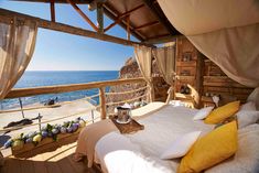 a bed sitting on top of a wooden floor next to the ocean with lots of windows