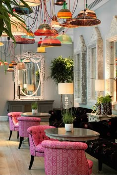 the interior of a restaurant with colorful chairs and lamps hanging from the ceiling, along with potted plants