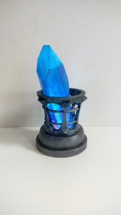 a blue glass object sitting on top of a white table next to a black stand