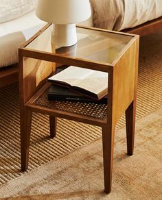 a wooden table with a book on it next to a bed