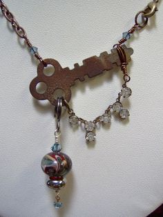 ♥') ¸.*'¸.**'¨) ¸. (¸.*' ♥ Imagine the stories these keys have told through the pages of time . . . Now a new story can begin . . . . . *  Fabulous Artisan Lampwork Beads - 12mm bead is made with metallic glass as well as the 9mm lampwork bead & wire wrapped in silver plated wire - they dangle from Vintage Skeleton Key   *  Vintage Antique Skeleton Key - Key has great patina - 2 inches long - with dangle of Lampwork Beads and Swarovski Crystals - a section of a Vintage Necklace with crystals is wire wrapped in brass wire and attached to the key and drapes from one side of the key to the other *  Lead and Nickle Free Copper Chain *  Brass Large Lobster Clasp  Necklace measures approximately 26 inches - with lampwork bead dangle about 32 inches.  Do you want it longer or shorter?  No problem Vintage Metal Jewelry With Keys Detail, Vintage Metal Jewelry With Keys, Vintage Pendant Jewelry With Keys, Vintage Key Necklaces As Gift, Vintage Metal Key Jewelry, Vintage Copper Necklace, Old Key Crafts, Antique Key Necklace, Key Crafts