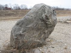 a large rock sitting on top of a gravel field